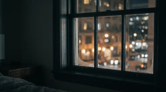 Vue nocturne d'une fenêtre de chambre avec lumière urbaine diffuse à travers le vitrage