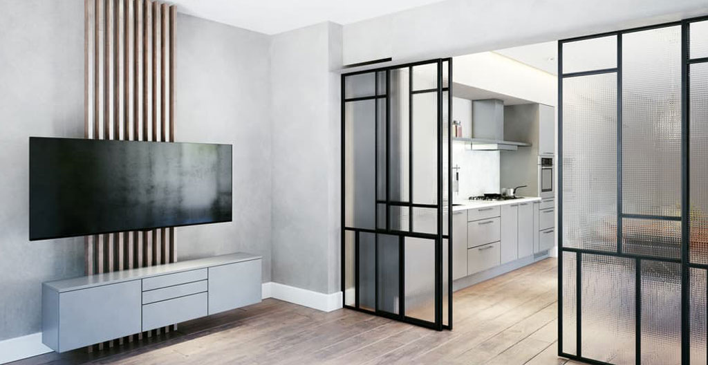 Une personne de dos fait coulisser une porte vitrée entre la cuisine et le salon dans un intérieur contemporain français