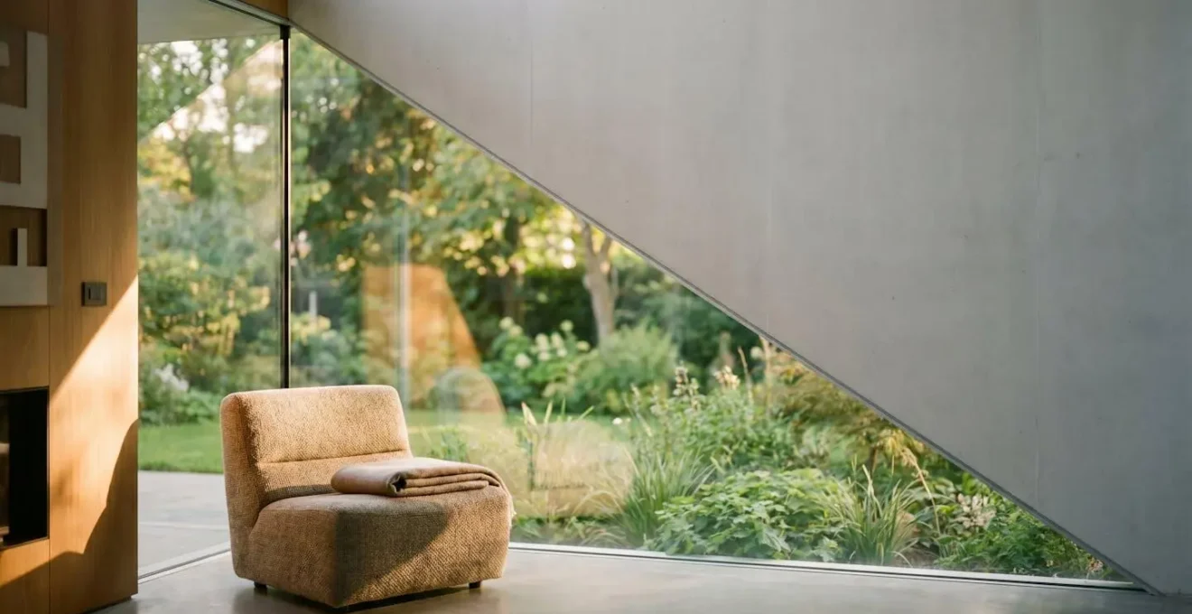 Grande baie vitrée d'angle minimaliste ouvrant un salon contemporain sur un jardin verdoyant, sans profilé apparent
